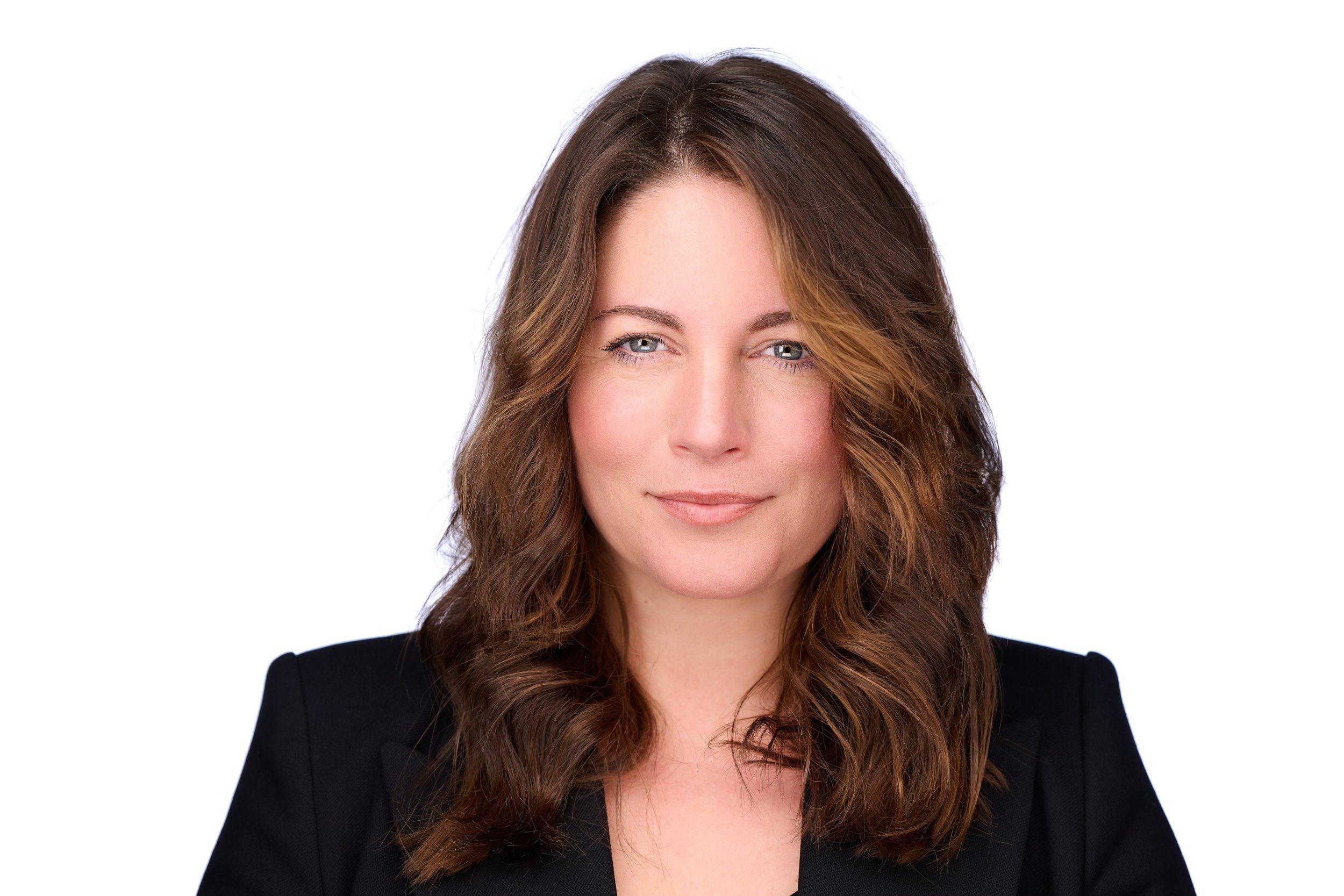 Headshot von Sarah für Ligne Roset: Frau mit braunen, gewellten Haaren im schwarzen Blazer vor weißem Hintergrund
